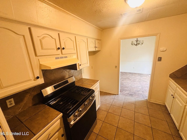 kitchen with tile counters, a textured ceiling, range hood, and stainless steel gas range