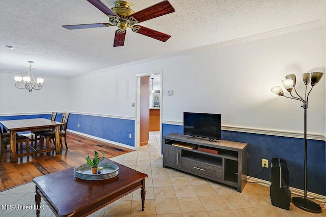 living area featuring ornamental molding, wainscoting, a textured ceiling, and light tile patterned flooring