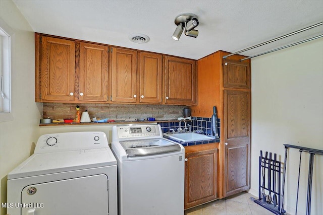 washroom featuring cabinet space, light tile patterned floors, visible vents, washer and dryer, and a sink