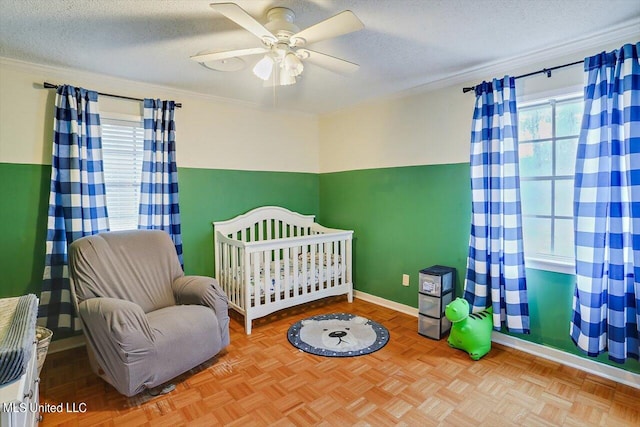 bedroom featuring crown molding, a nursery area, a textured ceiling, and ceiling fan