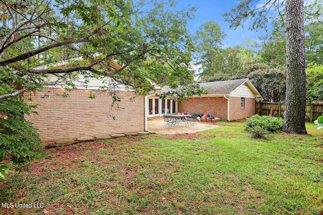 view of yard featuring a patio area, fence, and french doors