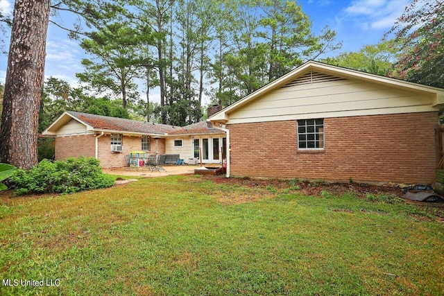 back of property featuring a yard, a patio, and brick siding