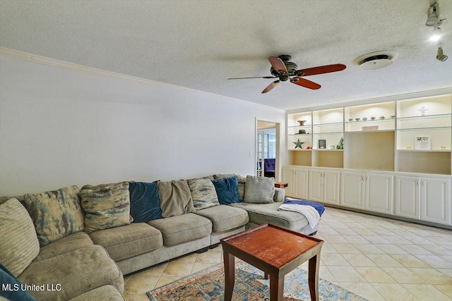 living room with a textured ceiling, ornamental molding, light tile patterned flooring, and a ceiling fan