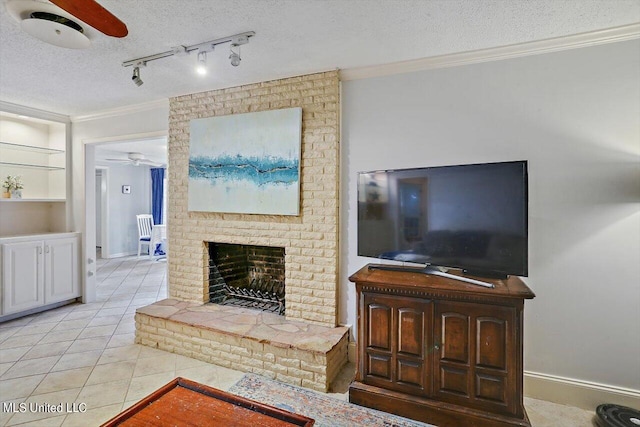 living room with crown molding, a ceiling fan, a brick fireplace, a textured ceiling, and tile patterned flooring