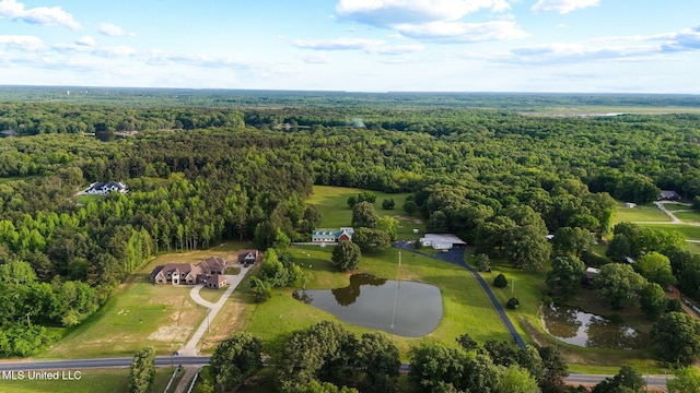 aerial view of property and surrounding area with a heavily wooded area and a nearby body of water