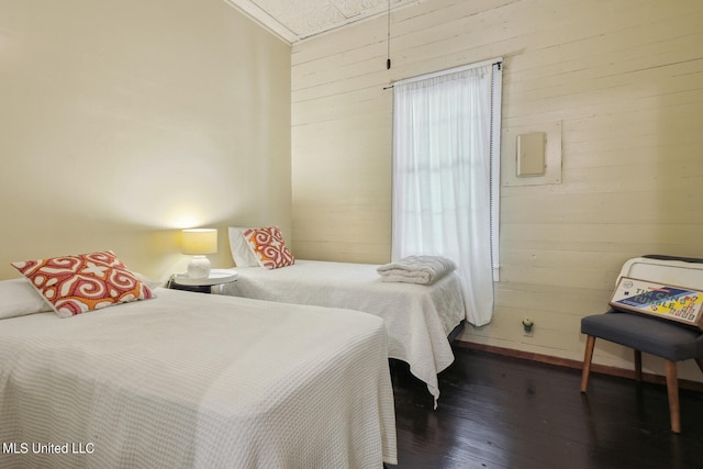 bedroom with wood walls and dark hardwood / wood-style flooring