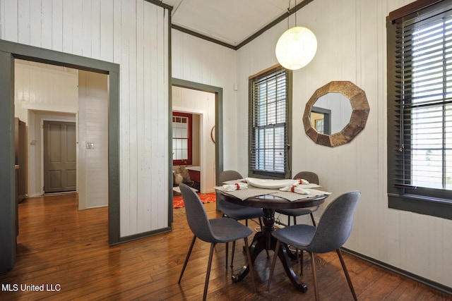 dining room featuring wooden walls, hardwood / wood-style flooring, and vaulted ceiling