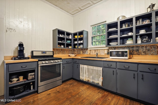 kitchen with ornamental molding, dark wood-type flooring, stainless steel range, sink, and butcher block countertops