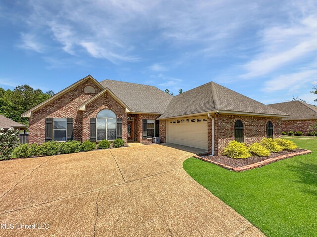 ranch-style house featuring a garage, a front lawn, roof with shingles, brick siding, and concrete driveway