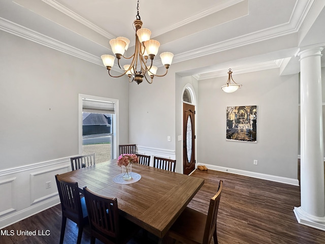 dining area featuring an inviting chandelier, crown molding, ornate columns, and wood finished floors