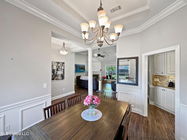 dining area featuring crown molding, a decorative wall, a fireplace, dark wood finished floors, and visible vents