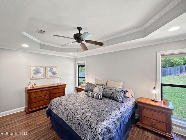bedroom featuring visible vents, ornamental molding, a tray ceiling, and dark wood-style floors