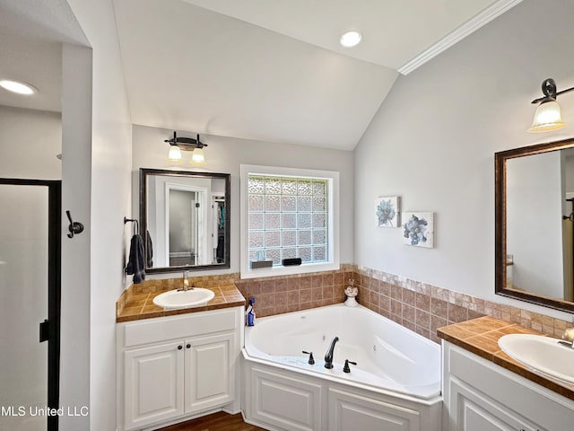 full bath featuring a sink, two vanities, a jetted tub, and lofted ceiling