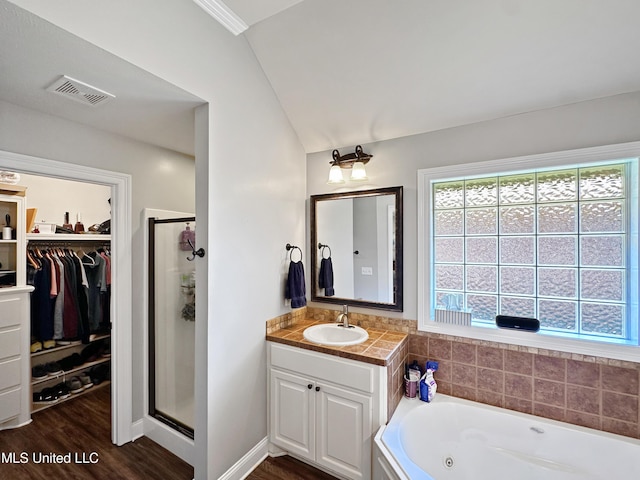 full bathroom with a walk in closet, visible vents, a shower stall, wood finished floors, and vanity