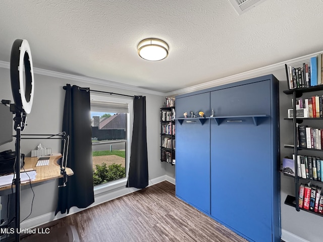 office space with a textured ceiling, visible vents, crown molding, wood finished floors, and baseboards
