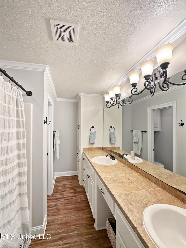 full bath with a sink, crown molding, wood finished floors, and visible vents
