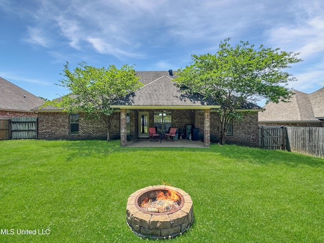 rear view of property featuring a fenced backyard, a lawn, an outdoor fire pit, and a patio area