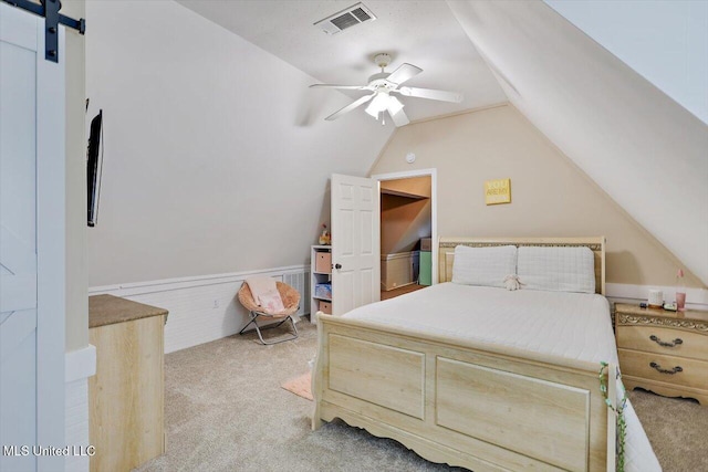 121 Countrywood Cir, Clinton, MS 39056 - bedroom with light carpet, lofted ceiling, a wainscoted wall, ceiling fan, and a barn door