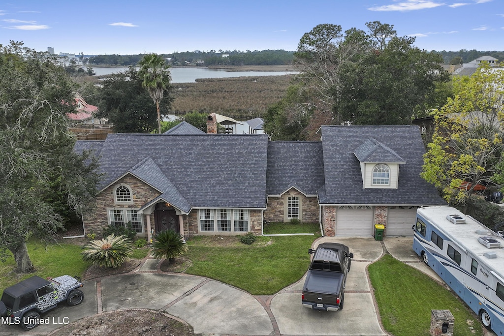view of front of property featuring driveway, a front lawn, a water view, a shingled roof, and stone siding