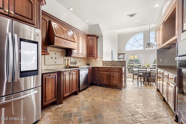 6313 Hermosa Dr, Ocean Springs, MS 39564 - kitchen with appliances with stainless steel finishes, custom range hood, tasteful backsplash, ceiling fan, and brick flooring