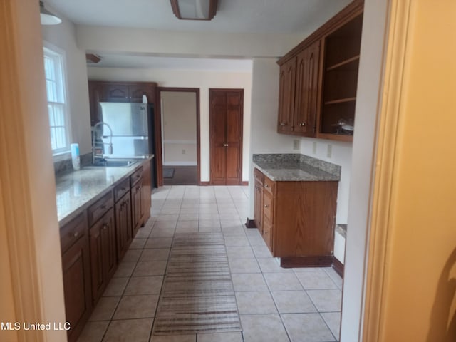 kitchen featuring light tile patterned floors, fridge, and sink