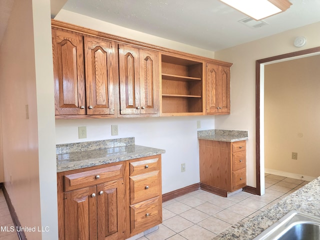 1618 Pear Orchard Pl, Jackson, MS 39211 - kitchen featuring visible vents, open shelves, brown cabinetry, light tile patterned floors, and baseboards