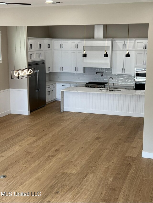 1851 Beach Blvd Unit 4, Biloxi, MS 39531 - kitchen with built in fridge, a sink, light wood-type flooring, light countertops, and white cabinetry