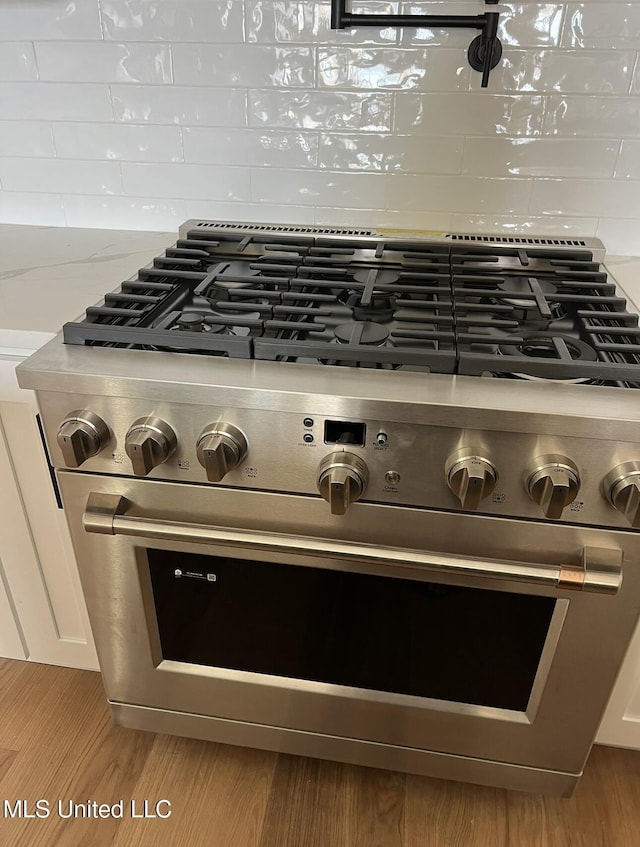 1851 Beach Blvd Unit 4, Biloxi, MS 39531 - kitchen view of stainless steel range, tasteful backsplash, wood finished floors, and light stone counters