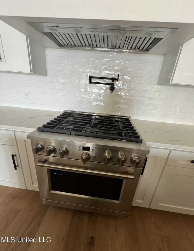 1851 Beach Blvd Unit 4, Biloxi, MS 39531 - kitchen view of white cabinets, decorative backsplash, extractor fan, and pot filler