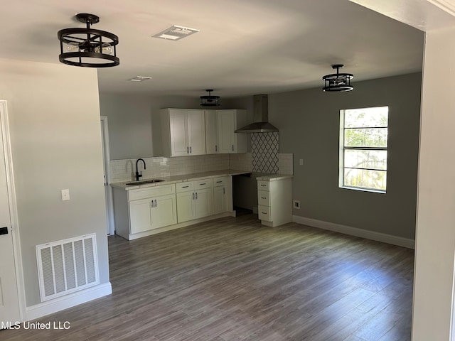 kitchen with white cabinetry, sink, wall chimney exhaust hood, backsplash, and light hardwood / wood-style floors