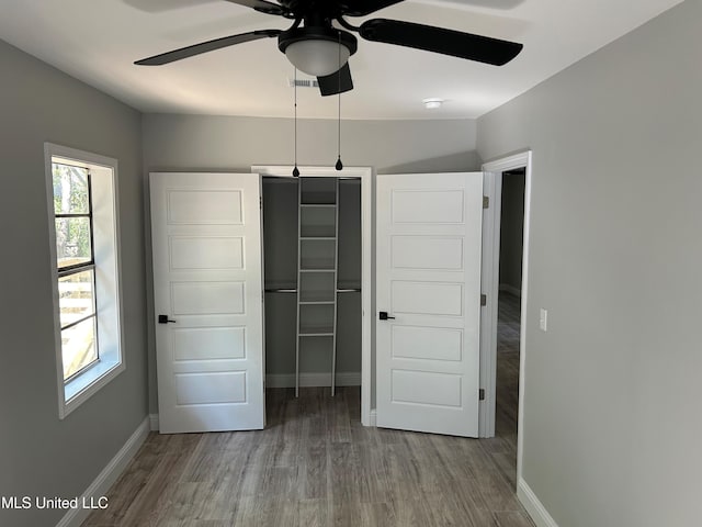 unfurnished bedroom with hardwood / wood-style flooring, ceiling fan, and a closet