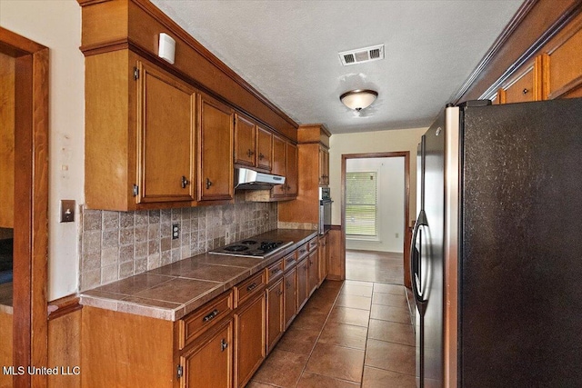 101 Lake Of Pines Dr, Jackson, MS 39206 - kitchen with freestanding refrigerator, wall oven, backsplash, and brown cabinets
