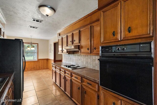 101 Lake Of Pines Dr, Jackson, MS 39206 - kitchen featuring black oven, brown cabinetry, wainscoting, under cabinet range hood, and wooden walls
