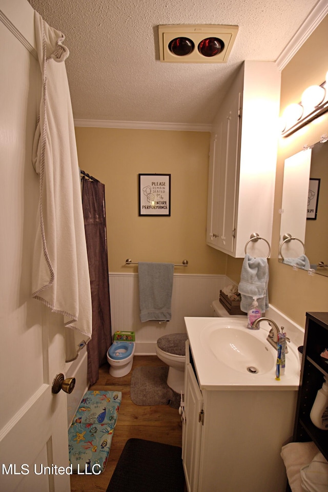 full bathroom featuring a textured ceiling, wood-type flooring, toilet, vanity, and crown molding