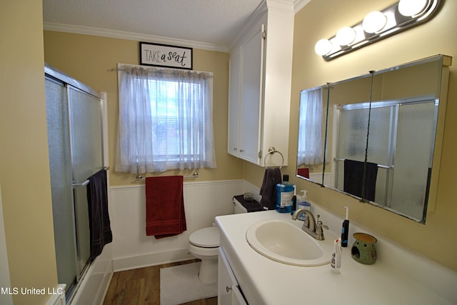 bathroom featuring a textured ceiling, hardwood / wood-style floors, toilet, vanity, and crown molding