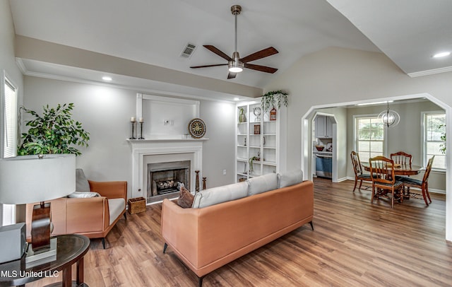 living room with visible vents, a fireplace, light wood finished floors, lofted ceiling, and ceiling fan