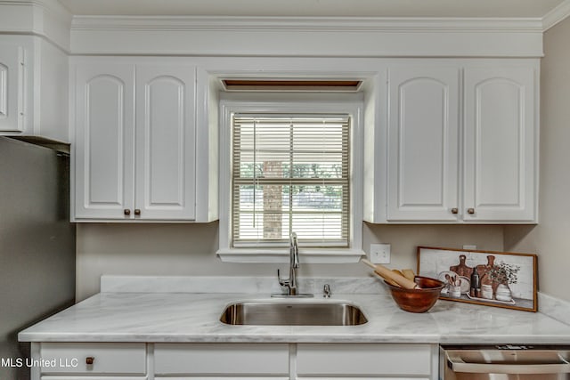 kitchen featuring dishwasher, white cabinets, freestanding refrigerator, and a sink