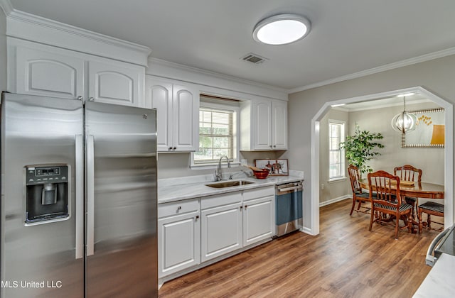 kitchen with visible vents, ornamental molding, a sink, stainless steel appliances, and light countertops