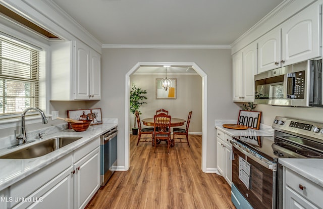 kitchen featuring crown molding, light countertops, arched walkways, stainless steel appliances, and a sink