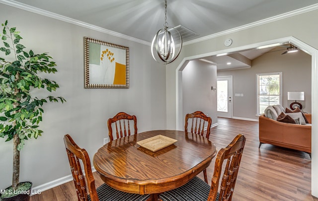 dining area featuring a notable chandelier, ornamental molding, wood finished floors, arched walkways, and baseboards