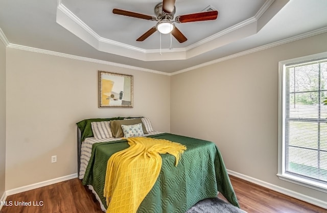 bedroom featuring a raised ceiling, crown molding, wood finished floors, and baseboards