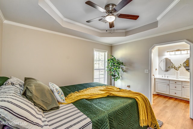 bedroom featuring visible vents, a sink, crown molding, light wood-style floors, and a raised ceiling