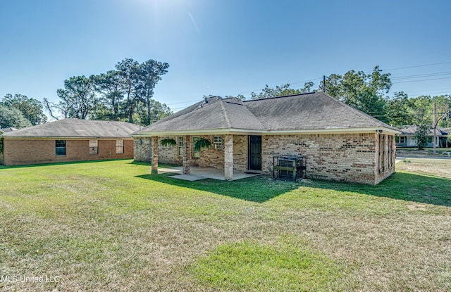 rear view of property with brick siding, a patio area, a lawn, and a shingled roof