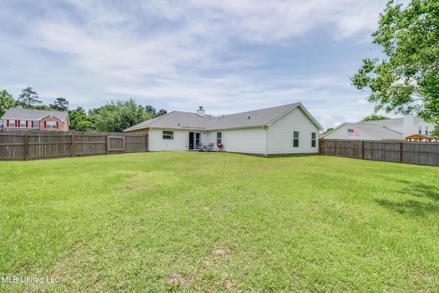 back of property with a lawn and a fenced backyard