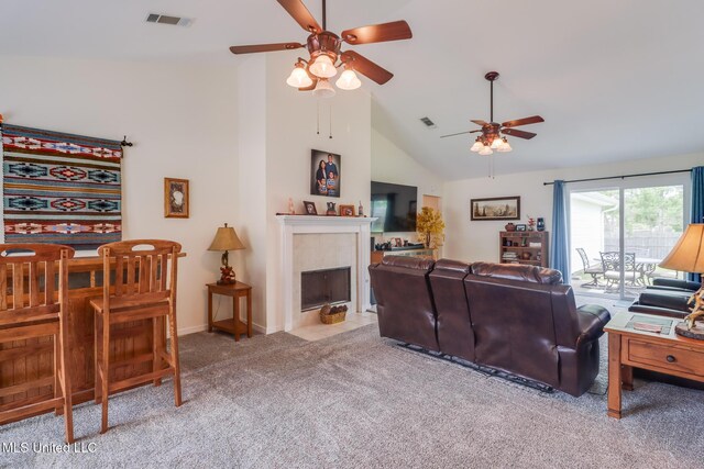 carpeted living area with visible vents, a ceiling fan, high vaulted ceiling, and a tile fireplace