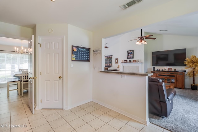 kitchen featuring visible vents, a peninsula, lofted ceiling, light tile patterned flooring, and ceiling fan with notable chandelier