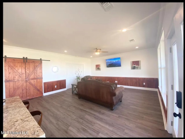 living room with ceiling fan, a barn door, and dark hardwood / wood-style floors