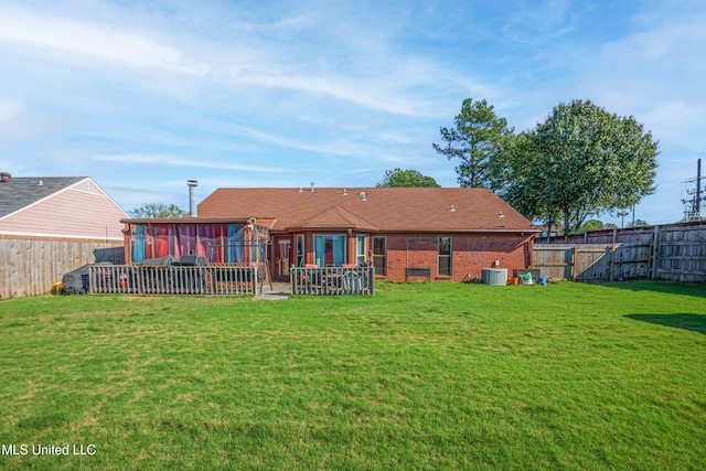 rear view of property featuring a yard, brick siding, and a fenced backyard