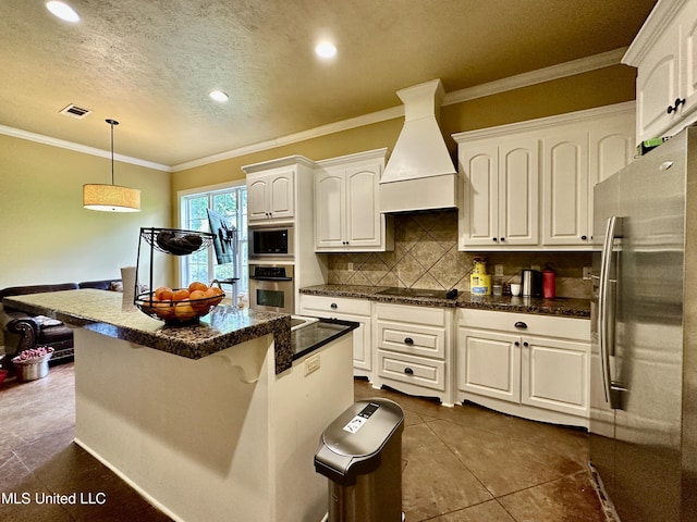 109 Brisage Dr, Madison, MS 39110 - kitchen featuring white cabinets, appliances with stainless steel finishes, hanging light fixtures, premium range hood, and backsplash