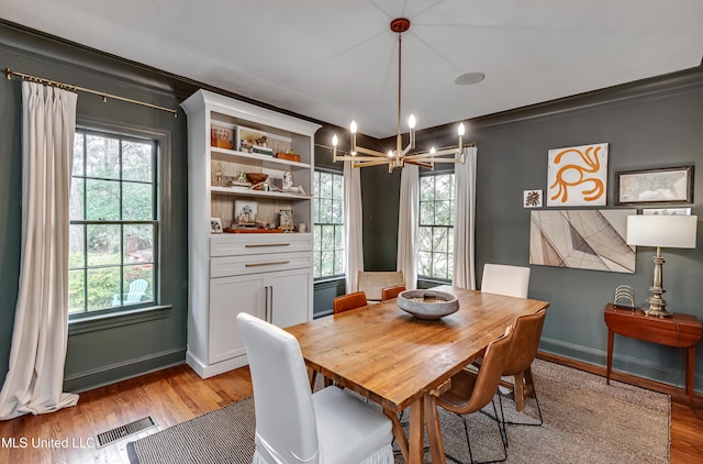 dining room with a wealth of natural light, ornamental molding, a chandelier, and light wood-type flooring